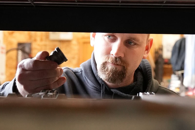 HVAC technician looking into an HVAC system performing maintenance.