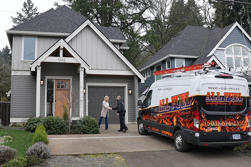 Tankless vs. Traditional Water Heaters: Which is Best for Your Home? Photo of a technician shaking a homeowner's hand in their driveway.