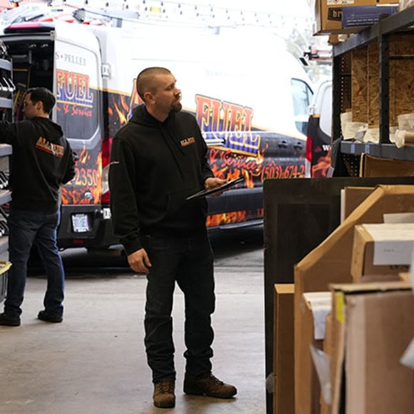 Two HVAC technicians carrying a box of new HVAC equipment out of their work van.