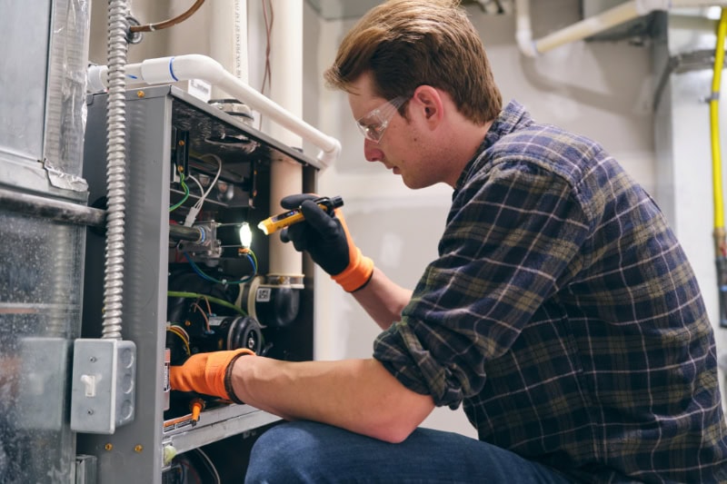 Technician performing HVAC maintenance on a furnace in Portland, OR.