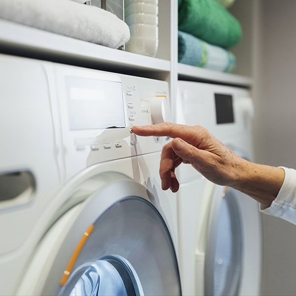 A hand pushing a button on a gas dryer.