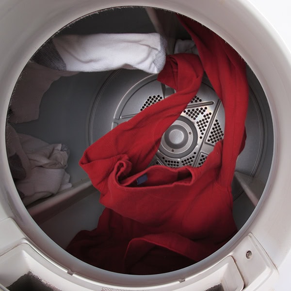 A hand pushing a button on a gas dryer.