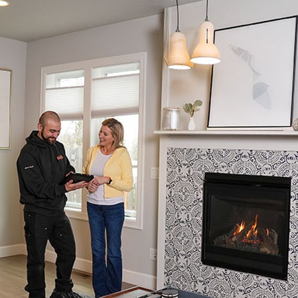 An HVAC technician showing a homeowner his ipad after a completed fireplace installation.