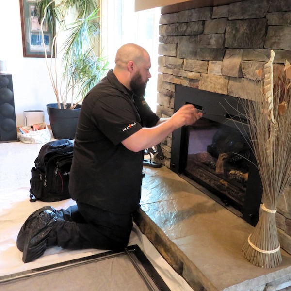 HVAC technician installing a gas fireplace in a home.