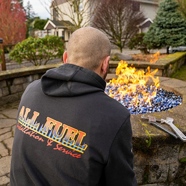 HVAC technician sitting in front of a recently installed outdoor fireplace.