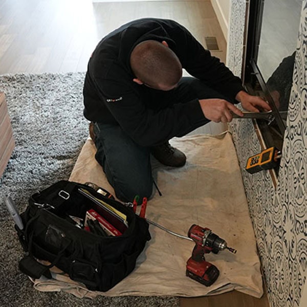 HVAC technician sitting in front of a recently installed outdoor fireplace.