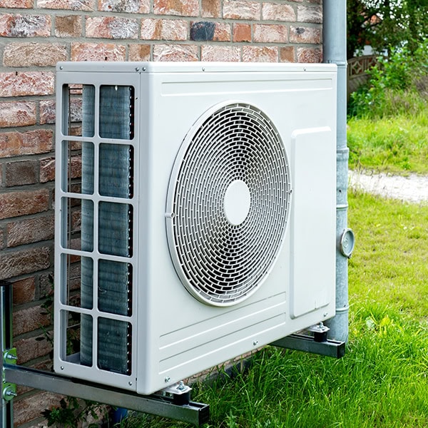 Newly installed heat pump outside a brick home.