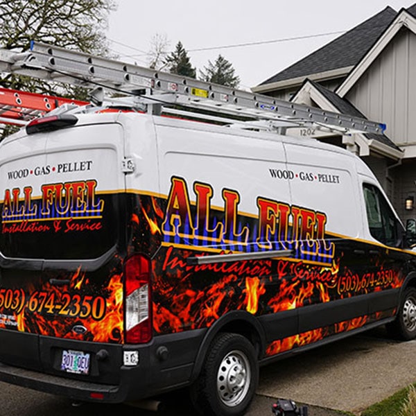 Two HVAC technicians pulling equipment out of their work van.
