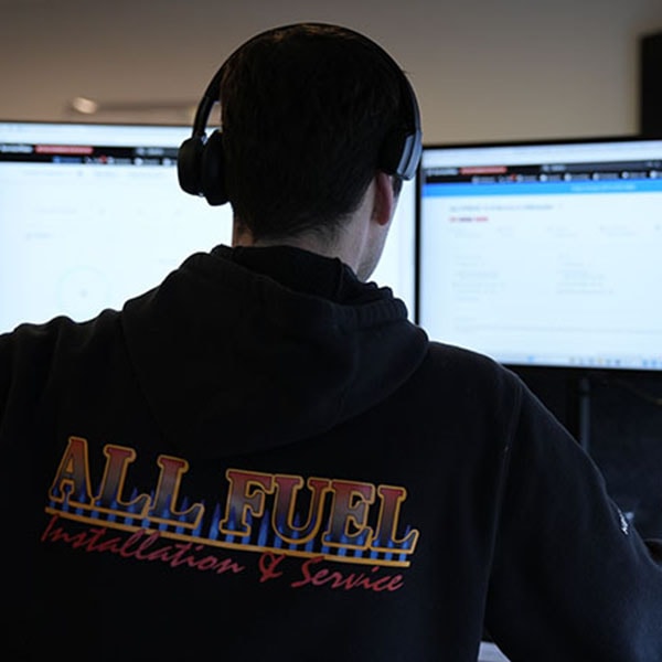 An office staff member sitting at a desk in front of a computer monitor, wearing a headset.
