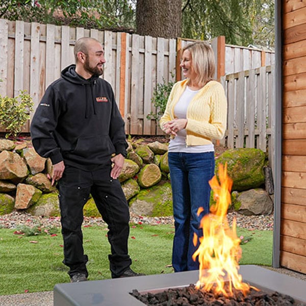 A gas fireplace with flames with a technician sitting behind it.