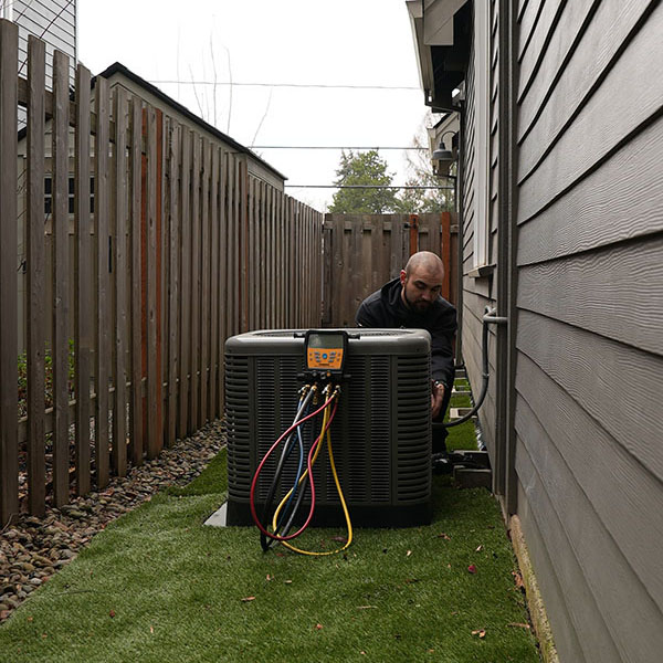HVAC technician grabbing his tool bag next to a furnace in a homes garage.