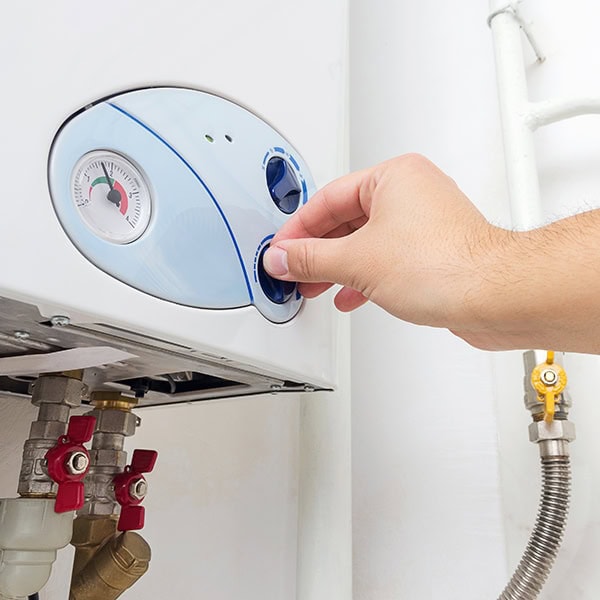 Homeowner turning a knob on a water heater.