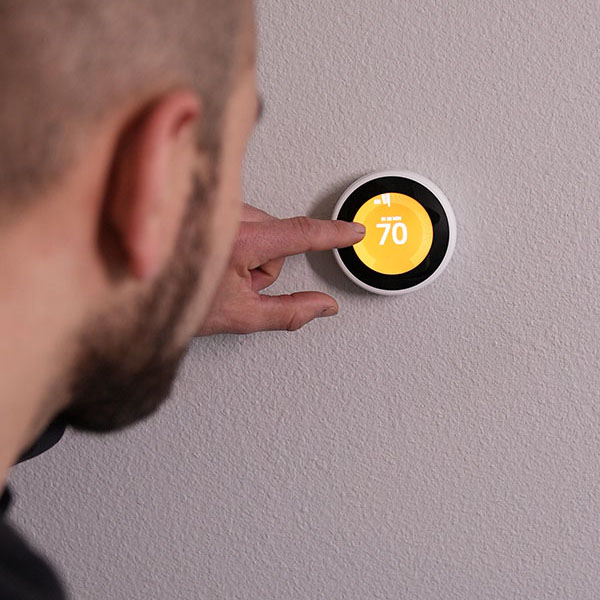 HVAC technician using a newly installed smart thermostat.
